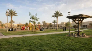 Granada Park in Qaryat Al Ulya Riyadh with green lawns, walking paths, playground slides and swings, seating areas, and families enjoying the park.