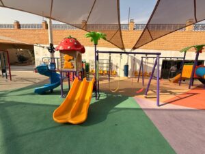 Outdoor playground setup for kids in Saudi Arabia with slides, swings, shade cover, and safety flooring