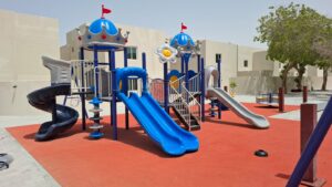 Outdoor playground with multiple slides and safety surface in a residential compound in Saudi Arabia