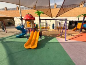 Corporate compound playground with slides, swings, shade structure, and rubber safety flooring in Saudi Arabia