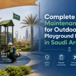 صيانة معدات ألعاب الحدائق الخارجية في السعودية، مع عامل يقوم بفحص سلامة منطقة الألعاب، والأرضيات، والزحاليق، والهياكل، ونقاط التثبيت.