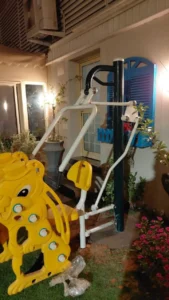 Outdoor fitness machine installed beside kids play equipment in a Saudi garden space with plants and outdoor activity area