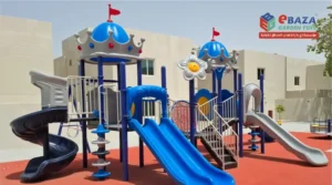 Outdoor playground equipment in Saudi Arabia with slides, climbing structure, rubber flooring, and shaded play towers by Ebaza Gardens.