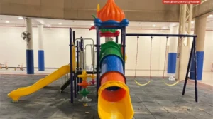 School playground with tube slide, straight slide, elevated play structure, and swing set.