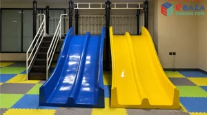 Colorful interlocking safety flooring under blue and yellow indoor playground slides with access stairs and climbing bars.