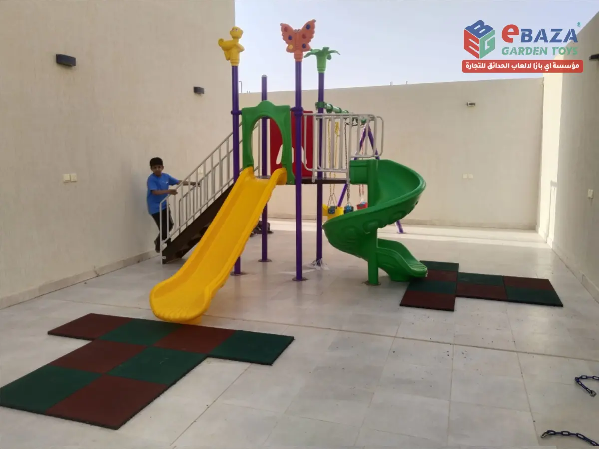 Child using a completed residential villa playground in Yanbu with a straight slide, spiral slide, steel staircase, and rubber safety flooring installed by Ebaza Gardens.