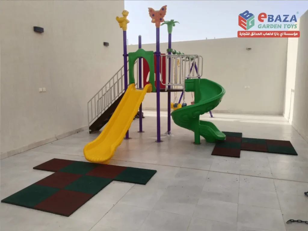 Completed residential villa playground in Yanbu featuring a multi-play unit with a straight slide, spiral slide, steel staircase, and rubber safety tiles installed by Ebaza Gardens.