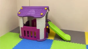 Colorful interlocking foam play mats under a purple kids playhouse with green slide in a safe indoor play area