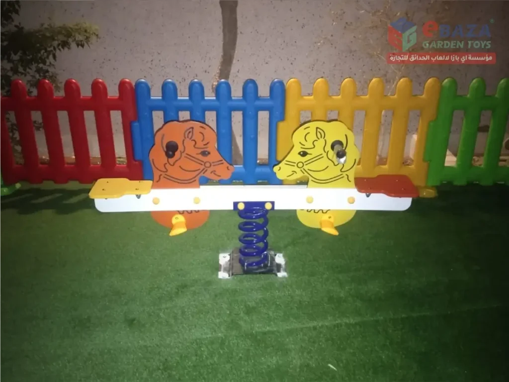 Colorful two-seat children’s spring seesaw with animal-shaped panels on artificial grass.