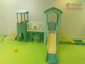 Indoor toddler slide with straight and curved slides, activity panels, basketball hoop, climbing features, and soft green flooring.