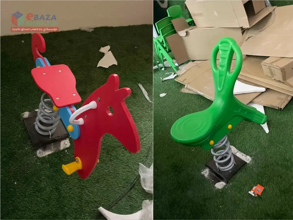 Red and green kids spring riders installed in an outdoor playground in Riyadh.