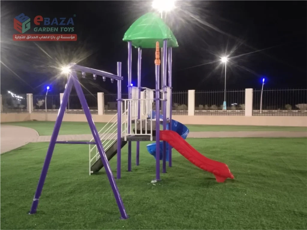 Outdoor playground installation in Madina with red straight slide, blue spiral slide, green canopy roof, white guardrails and purple swing frame