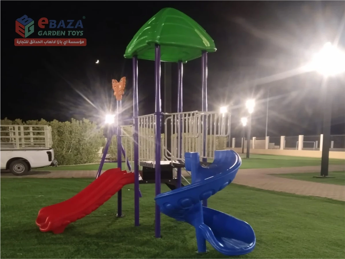 Outdoor playground installation in Madina featuring a blue spiral slide, red double slide, green canopy roof and purple steel frame