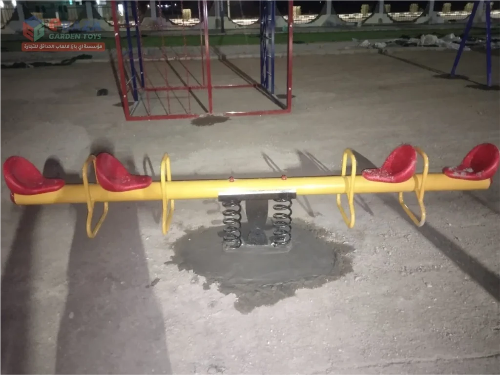 Four-seat spring seesaw with molded seats and twin spring base installed in a public park in Madina.