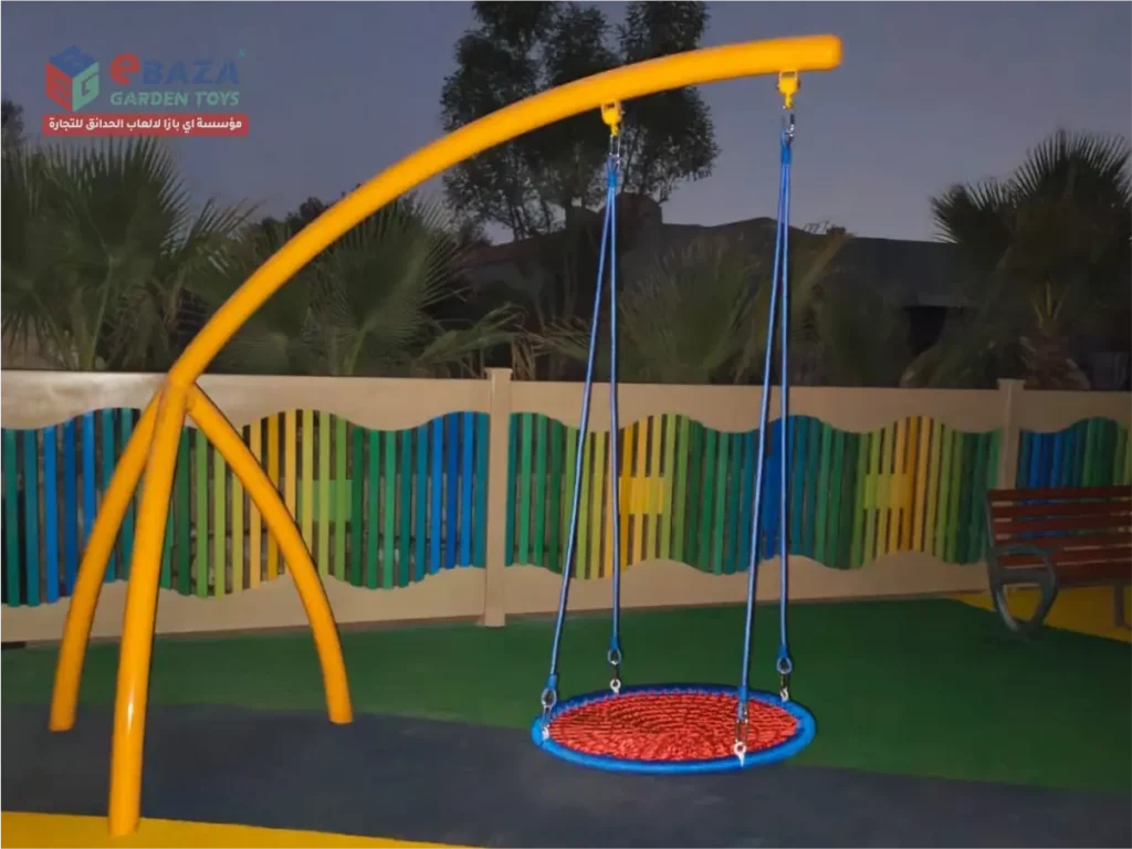 Circular basket swing installed at a private farmhouse playground in Al Kharj with a curved metal frame and colorful safety flooring.