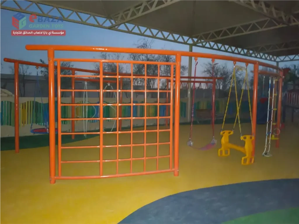 Outdoor playground installation in Al Kharj with metal climbing frame, kids’ swings, rope ladder, gym rings and shaded safety flooring.